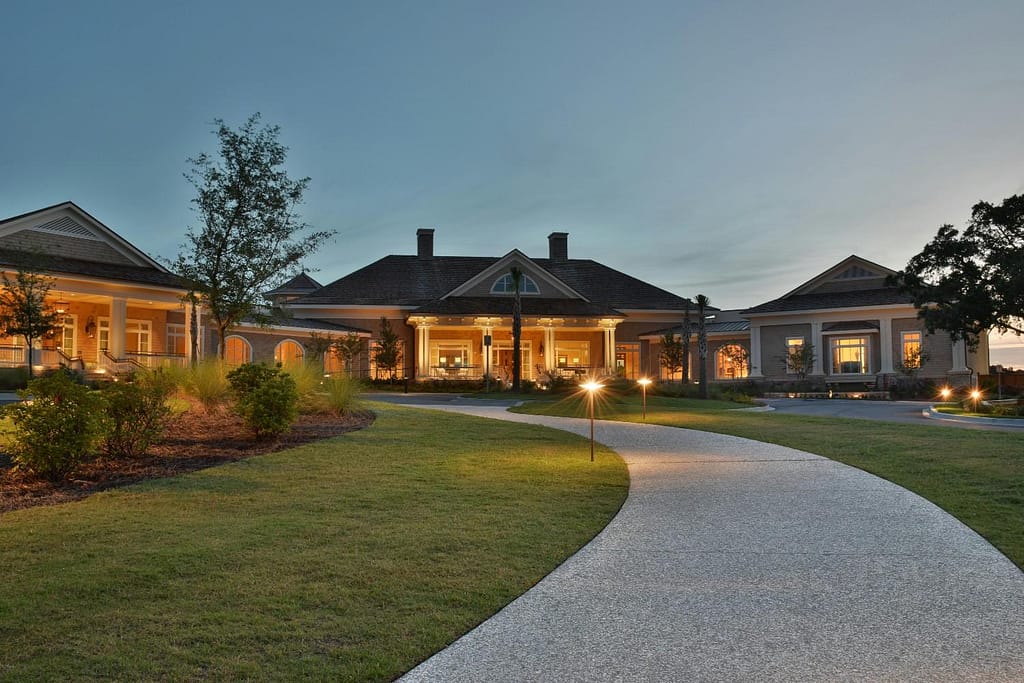 Well-kept lawn and landscaped entry path outside a large Madison property at dusk.