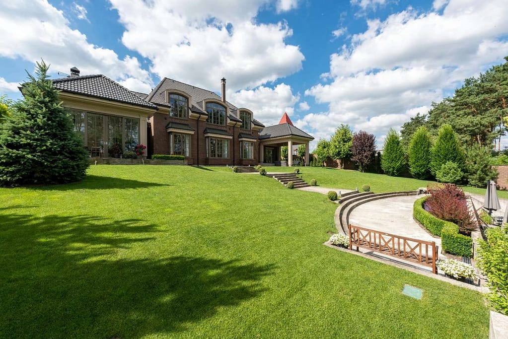 Large Milwaukee home with a manicured lawn, trimmed hedges, and landscaped patio showcasing professional landscape maintenance.