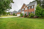 Neatly maintained front yard with green lawn, trimmed shrubs, and landscaped beds surrounding a brick suburban home in Delafield