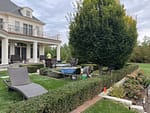 Landscapers trimming hedges and maintaining a well-manicured yard outside a large home in a North Shore neighborhood.