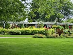 Well-maintained garden with lush green lawn, colorful flower beds, and a white pergola in a landscaped outdoor space in Delafield