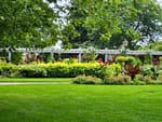 Professionally landscaped community green space with lush lawn, colorful flower beds, and mature trees in Whitefish Bay.