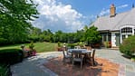 Outdoor dining area with maintained hardscape surfaces, surrounding plant health, clean transitions between lawn and patio, and large amounts of flower containers that fill the space with color.