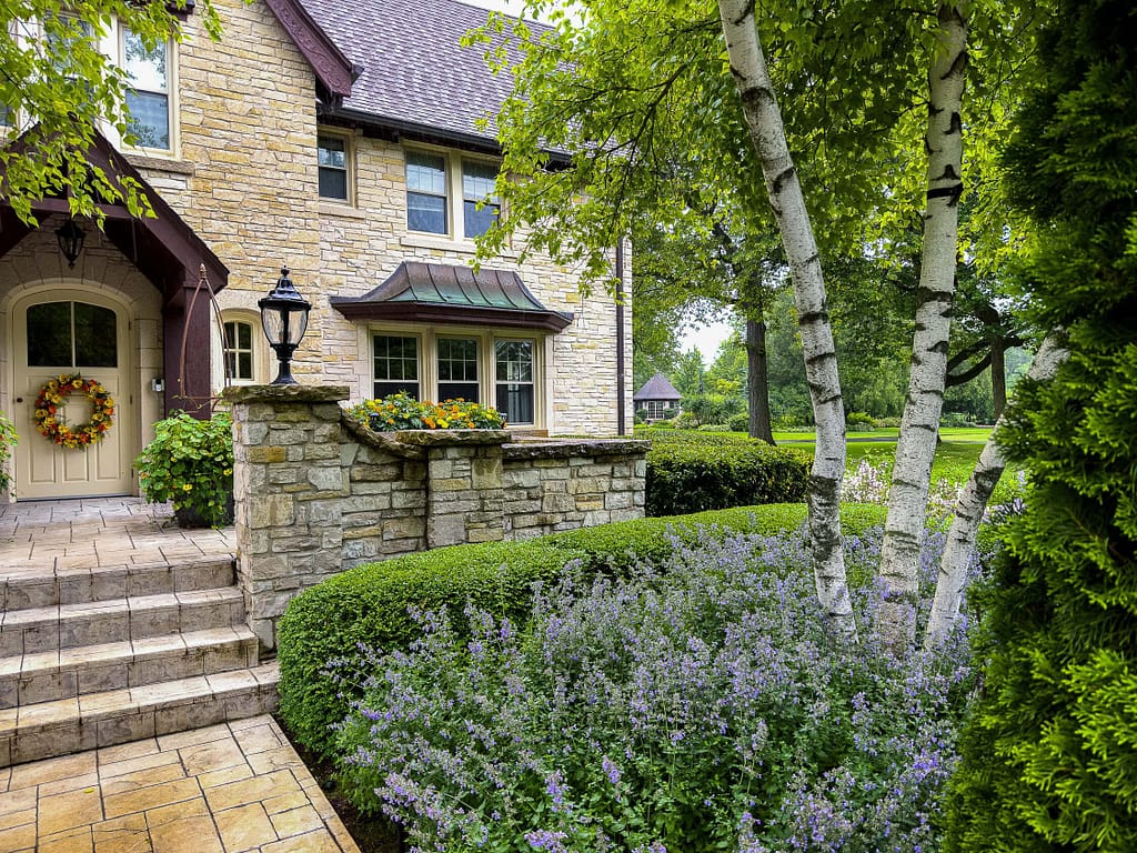 Boxwoods, Nepeta, and bright marigolds form a structured yet welcoming front entrance—showing the impact of regular bed maintenance and seasonal color rotations.